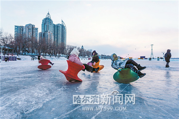 松花江畔,游人参加冰上游乐项目.